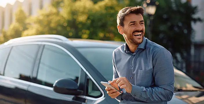 Man leaning on car with phone